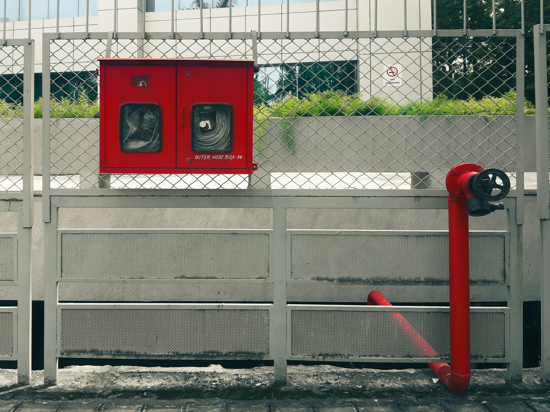 a red fire hydrant sitting next to a metal fence